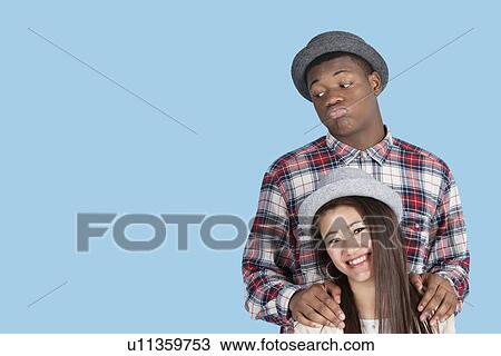 Bored African American man with smiling girlfriend over blue background View Large Photo Image Stock Image - Bored African American man with smiling girlfriend over blue background. Fotosearch