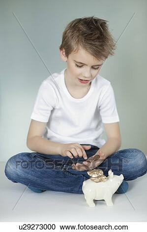 Boy with piggy bank counting coins over gray background View Large Photo Image Stock Image - Boy with piggy bank counting coins over gray background. Fotosearch