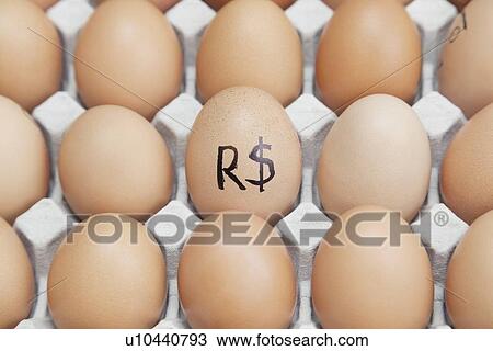 Stock Image - Brazilian currency sign on egg surrounded by plain brown eggs in carton. Fotosearch