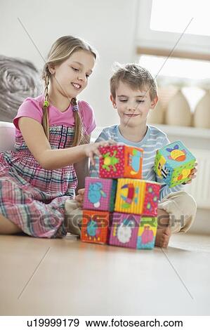 Stock Photo - Children stacking blocks while sitting on floor. Fotosearch