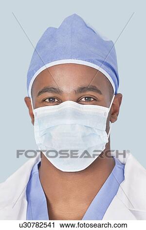 Close-up of a male surgeon wearing mask over light blue background View Large Photo Image Stock Image - Close-up of a male surgeon wearing mask over light blue background. Fotosearch