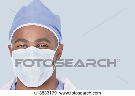 Close-up of a male surgeon wearing mask over light blue background View Large Photo Image Stock Photo - Close-up of a male surgeon wearing mask over light blue background. Fotosearch