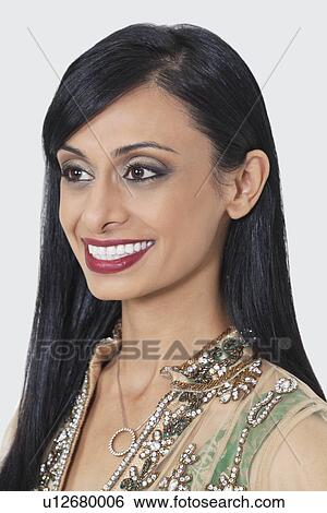 Stock Photograph - Close-up of an attractive Indian woman looking away over gray background. Fotosearch