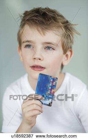 Close-up of little boy holding credit card over gray background View Large Photo Image Stock Photo - Close-up of little boy holding credit card over gray background. Fotosearch