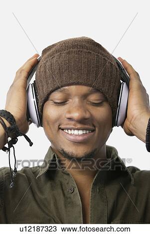 Close-up of relaxed young man listening music through headphones View Large Photo Image Stock Image - Close-up of relaxed young man listening music through headphones. Fotosearch