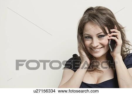 Close-up portrait of a young woman on call over gray background View Large Photo Image Picture - Close-up portrait of a young woman on call over gray background. Fotosearch