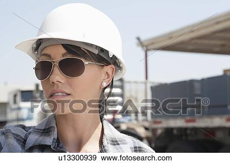 Close-up view of female industrial worker wearing hardhat and sunglasses View Large Photo Image Stock Photo - Close-up view of female industrial worker wearing hardhat and sunglasses. Fotosearch