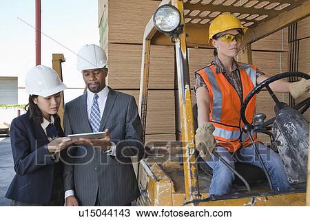 Engineers using tablet PC with female industrial worker driving forklift truck View Large Photo Image Stock Image - Engineers using tablet PC with female industrial worker driving forklift truck. Fotosearch