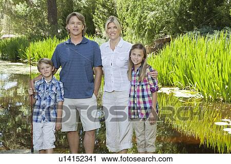 Family portrait of four standing against lake View Large Photo Image Stock Image - Family portrait of four standing against lake. Fotosearch