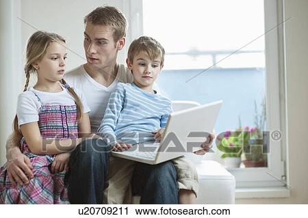 Father and children using laptop while sitting on chair View Large Photo Image Stock Image - Father and children using laptop while sitting on chair. Fotosearch