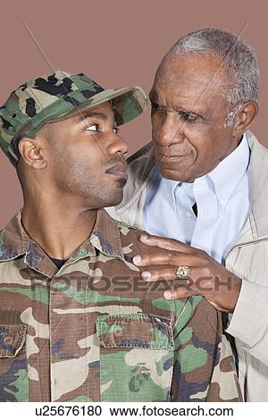 Stock Image - Father and US Marine Corps soldier looking at each other over brown background. Fotosearch