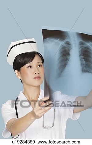 Female doctor analyzing x-ray report over light blue background View Large Photo Image Stock Photo - Female doctor analyzing x-ray report over light blue background. Fotosearch