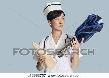 Stock Photo - Female doctor holding prosthesis foot over light blue background. Fotosearch