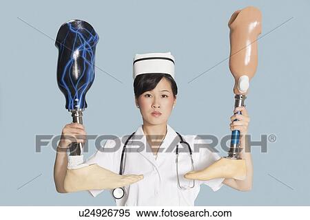 Stock Photography - Female doctor holding up two artificial legs over light blue background. Fotosearch