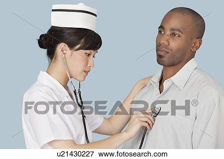 Female doctor listening the heartbeat of male patient over light blue background View Large Photo Image Stock Photo - Female doctor listening the heartbeat of male patient over light blue background. Fotosearch