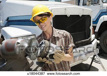 Stock Photo - Female industrial worker buffing a truck engine cylinder. Fotosearch