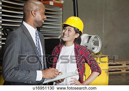 Female industrial worker looking at male inspector as he writes on clipboard View Large Photo Image Stock Image - Female industrial worker looking at male inspector as he writes on clipboard. Fotosearch