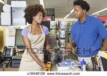 Female store clerk looking at customer while scanning product at super market View Large Photo Image Stock Photograph - Female store clerk looking at customer while scanning product at super market. Fotosearch