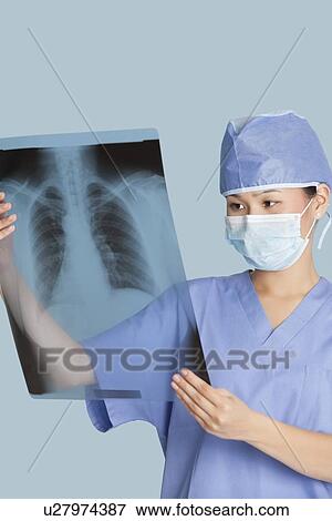 Stock Photo - Female surgeon analyzing x-ray report over light blue background. Fotosearch