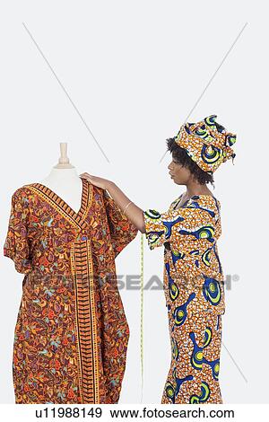 Female tailor in traditional outfit measuring dashiki on tailor's dummy over gray background View Large Photo Image Stock Photo - Female tailor in traditional outfit measuring dashiki on tailor's dummy over gray background. Fotosearch