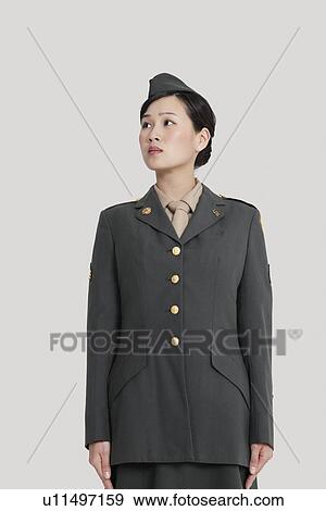 Stock Photo - Female US military officer standing in attention as she looks away over gray background. Fotosearch