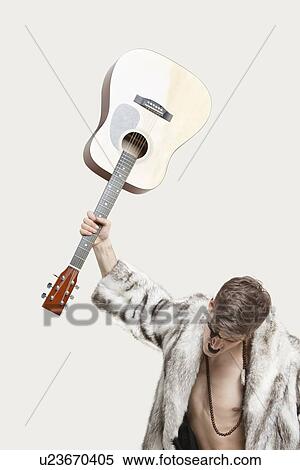 Frustrated young man in fur coat about to throw his guitar against gray background View Large Photo Image Stock Photography - Frustrated young man in fur coat about to throw his guitar against gray background. Fotosearch