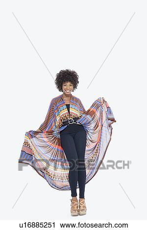 Stock Image - Full length portrait of an attractive African American in traditional wear standing over gray background. Fotosearch