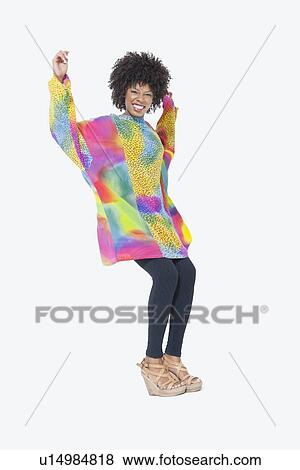 Stock Photo - Full length portrait of happy African American woman in dashiki dancing over gray background. Fotosearch