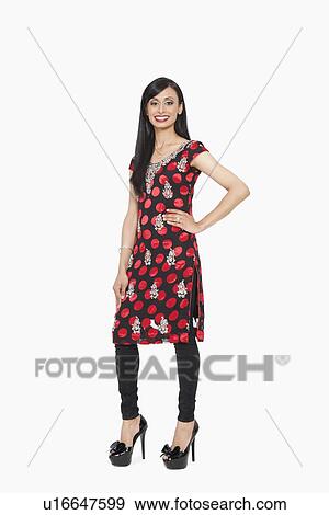 Stock Photo - Full length portrait of Indian female in traditional wear standing with hand on hip over gray background. Fotosearch