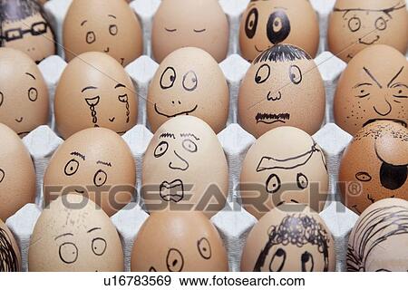 Stock Photo - Funny faces on painted on brown eggs arranged in carton. Fotosearch
