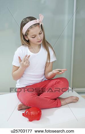 Girl with red piggy bank counting coins on bed View Large Photo Image Stock Photo - Girl with red piggy bank counting coins on bed. Fotosearch