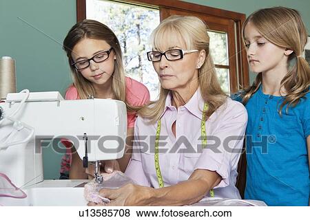 Granddaughters looking at grandmother sewing cloth View Large Photo Image Stock Photo - Granddaughters looking at grandmother sewing cloth. Fotosearch