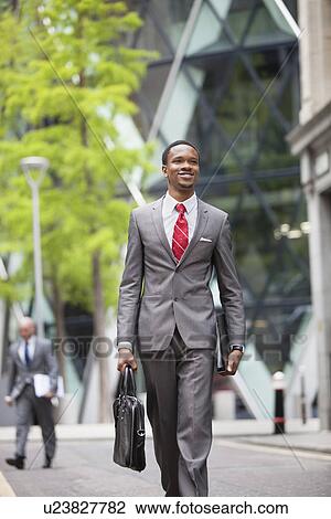 Happy African American businessman with bag walking on street View Large Photo Image Stock Image - Happy African American businessman with bag walking on street. Fotosearch