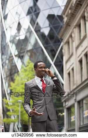 Happy businessman using cell phone outside building View Large Photo Image Stock Photograph - Happy businessman using cell phone outside building. Fotosearch