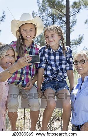 Happy family taking self portrait through cell phone outdoors View Large Photo Image Stock Photo - Happy family taking self portrait through cell phone outdoors. Fotosearch