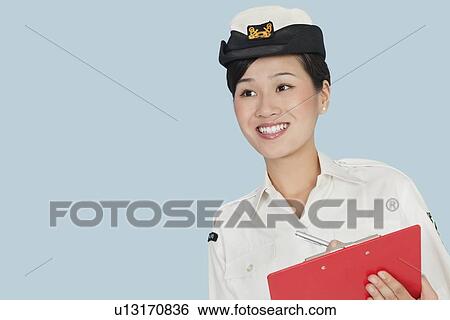 Happy female US Navy officer with clipboard smiling over light blue background View Large Photo Image Stock Photograph - Happy female US Navy officer with clipboard smiling over light blue background. Fotosearch