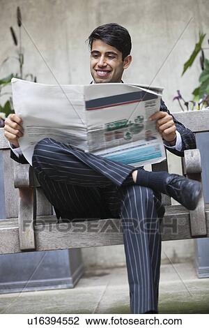 Happy Indian businessman reading newspaper while sitting on bench View Large Photo Image Stock Image - Happy Indian businessman reading newspaper while sitting on bench. Fotosearch