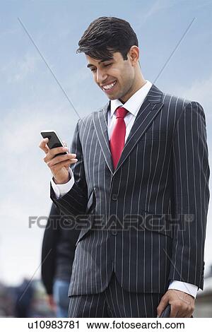 Stock Image - Happy Indian businessman using cell phone. Fotosearch