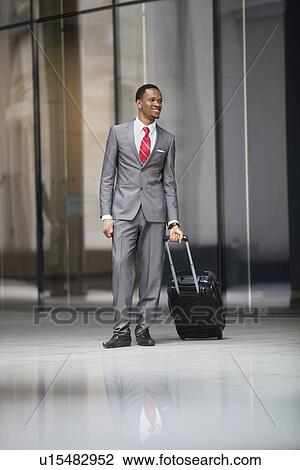 Stock Image - Happy male executive with luggage on a business trip. Fotosearch
