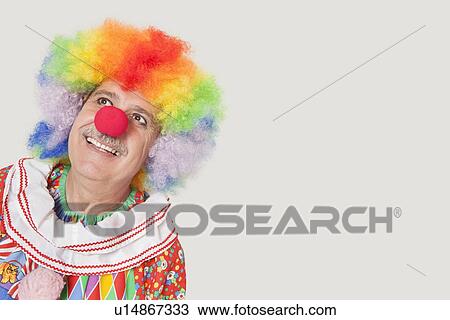 Happy senior clown looking up against gray background View Large Photo Image Stock Image - Happy senior clown looking up against gray background. Fotosearch