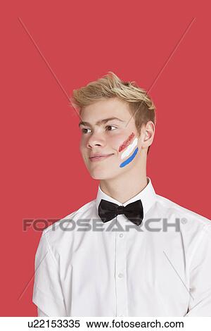 Stock Photography - Happy young man with Dutch flag painted on his face over red background. Fotosearch