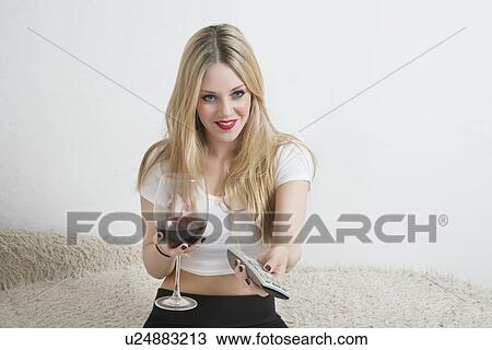 Happy young woman holding wine glass while watching television View Large Photo Image Stock Image - Happy young woman holding wine glass while watching television. Fotosearch