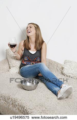 Happy young woman with wine glass sitting on sofa View Large Photo Image Stock Photography - Happy young woman with wine glass sitting on sofa. Fotosearch