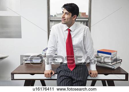 Indian businessman leaning on desk while looking away in office View Large Photo Image Stock Image - Indian businessman leaning on desk while looking away in office. Fotosearch