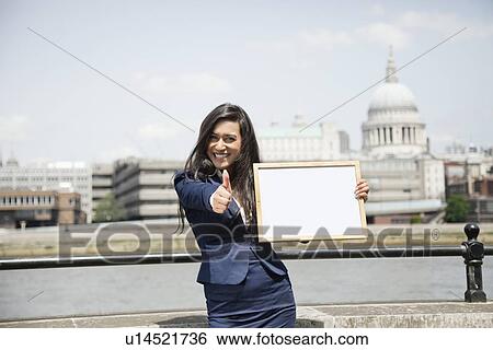 Indian businesswoman gesturing thumbs up as she holds Moodboard sign with St. Paul's Cathedral in background View Large Photo Image Stock Photograph - Indian businesswoman gesturing thumbs up as she holds Moodboard sign with St. Paul's Cathedral in background. Fotosearch