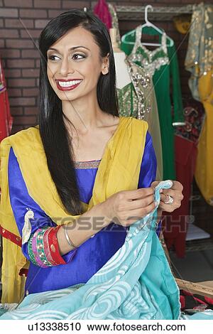 Indian female dressmaker looking away while holding sari View Large Photo Image Stock Image - Indian female dressmaker looking away while holding sari. Fotosearch