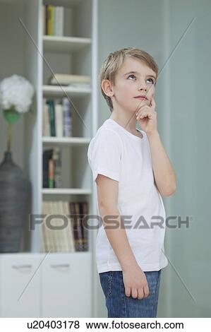 Stock Photo - Little boy lost in thoughts at home. Fotosearch