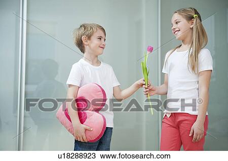 Little boy with heart shape cushion giving flower to girl View Large Photo Image Stock Image - Little boy with heart shape cushion giving flower to girl. Fotosearch
