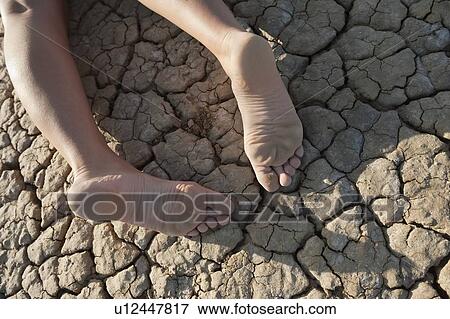 Low section of a woman lying on cracked land View Large Photo Image Stock Photo - Low section of a woman lying on cracked land. Fotosearch