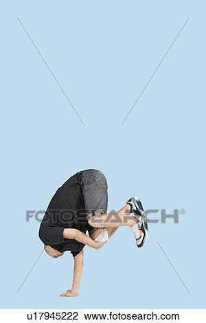 Male break dancer balances upside down on one hand over blue background View Large Photo Image Stock Image - Male break dancer balances upside down on one hand over blue background. Fotosearch
